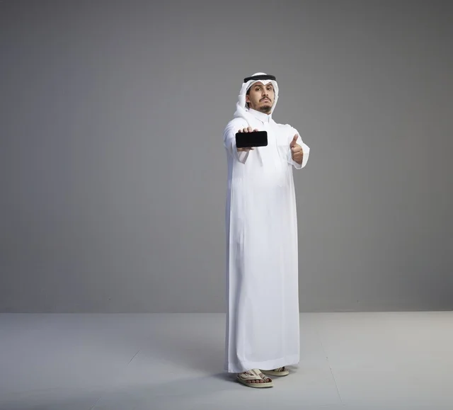 Saudi Man Holding Blank Smartphone Screen with Thumbs Up