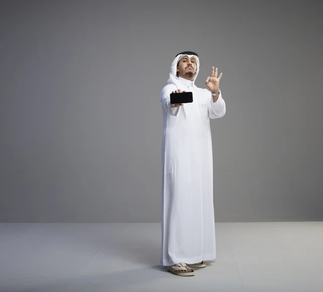 Saudi Man Holding Blank Smartphone Screen with Okay Sign