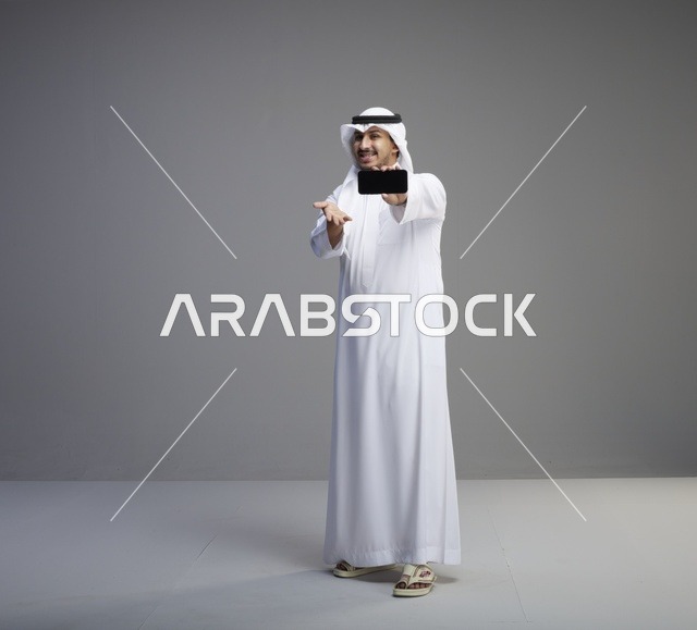 رجل سعودي يمسك هاتف ذكي بشاشة فارغة