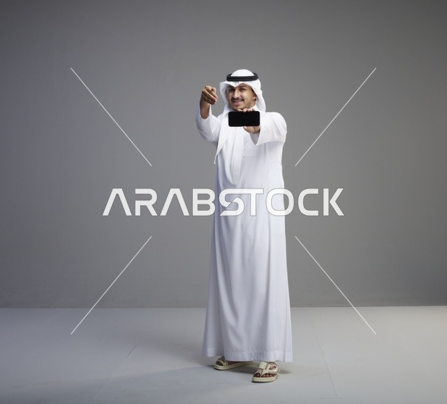 رجل سعودي يحمل هاتف ذكي بشاشة فارغة