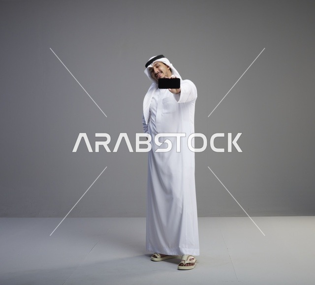 رجل سعودي يحمل هاتف ذكي بشاشة فارغة في الاستوديو