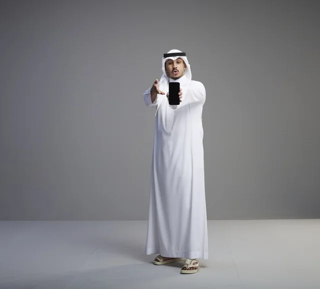 Saudi Man Holding Smartphone with Blank Screen in Studio