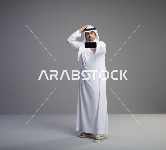 رجل سعودي يحمل هاتف ذكي بشاشة فارغة في استوديو