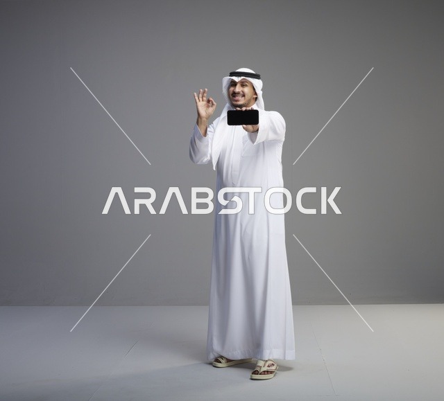 رجل سعودي يحمل هاتف ذكي بشاشة فارغة في استوديو