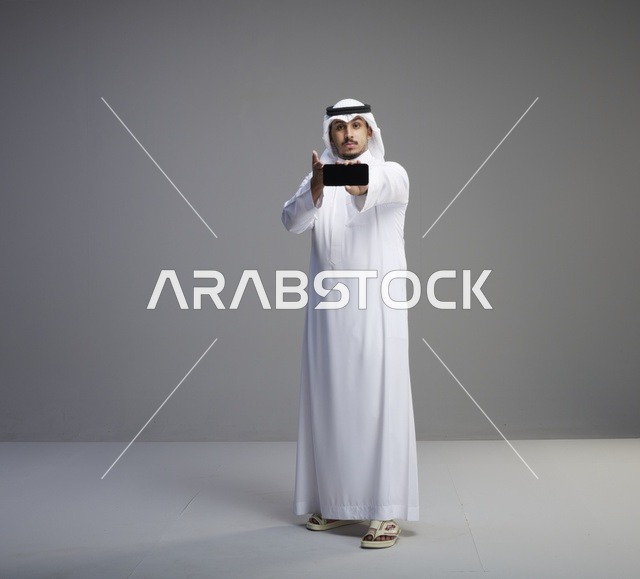رجل سعودي يمسك هاتف بشاشة فارغة في الاستوديو
