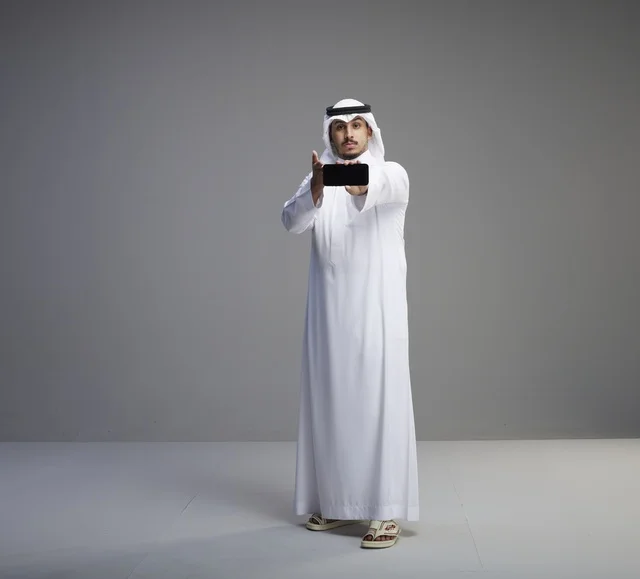 رجل سعودي يمسك هاتف بشاشة فارغة في الاستوديو