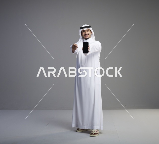 رجل سعودي يمسك هاتف بشاشة فارغة في الاستوديو