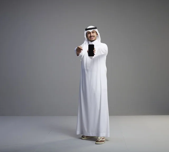 رجل سعودي يمسك هاتف بشاشة فارغة في الاستوديو