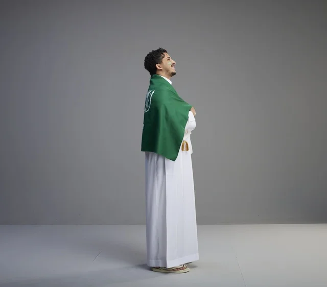 Saudi Man Draped in National Flag on Grey Background