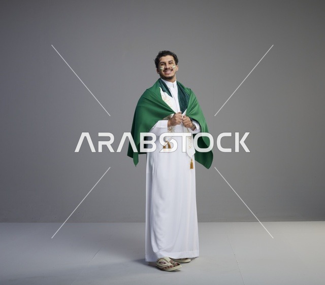 شاب سعودي يلتف بعلم المملكة في الاستوديو