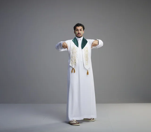 شاب سعودي بملابس اليوم الوطني يشير للأسفل