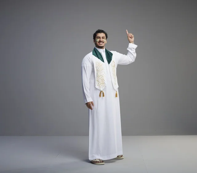 شاب سعودي بملابس اليوم الوطني يشير للأعلى