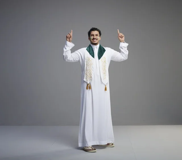 شاب سعودي بالزي الوطني يشير للأعلى في الاستوديو