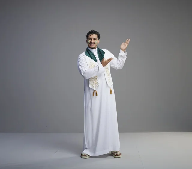 شاب سعودي بملابس احتفالية وطنية يشير بيده