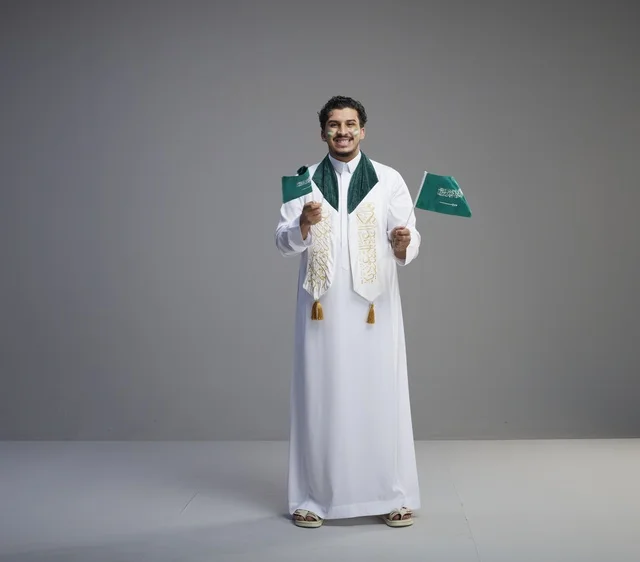 شاب سعودي يحتفل باليوم الوطني حاملاً الأعلام في الاستوديو