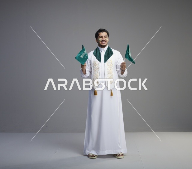 شاب سعودي يحمل الأعلام للاحتفال باليوم الوطني