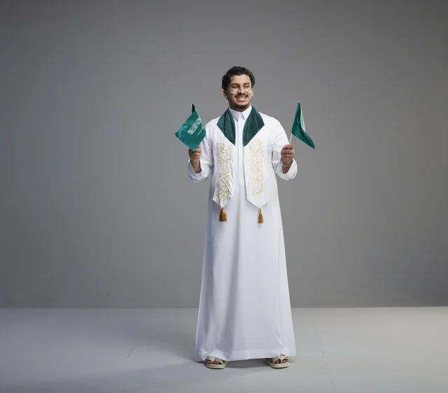 شاب سعودي يحمل الأعلام للاحتفال باليوم الوطني