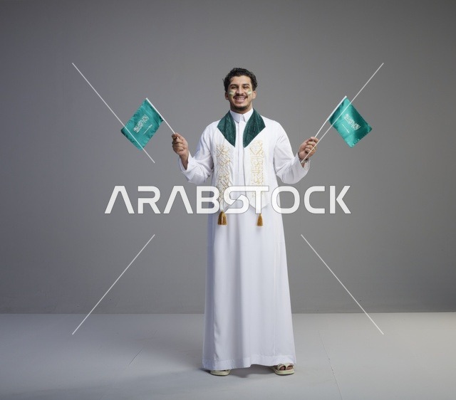شاب سعودي يحتفل بالأعلام السعودية في الاستوديو