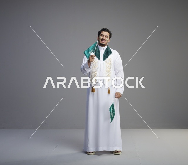 شاب سعودي يحمل الأعلام الوطنية في استوديو