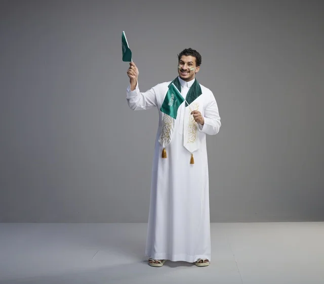 Saudi Man Celebrating with National Flags on Grey Background