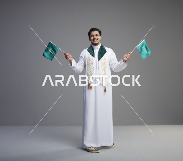 شاب سعودي يحمل الأعلام الوطنية احتفالاً باليوم الوطني