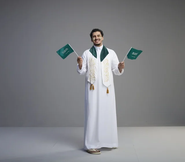 شاب سعودي يحتفل بالأعلام الوطنية في الاستوديو