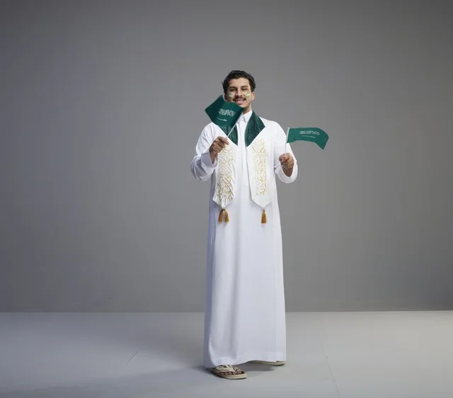شاب سعودي يحتفل باليوم الوطني بالأعلام في استوديو