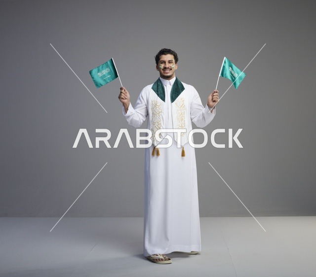 شاب سعودي يحمل الأعلام السعودية في احتفال وطني