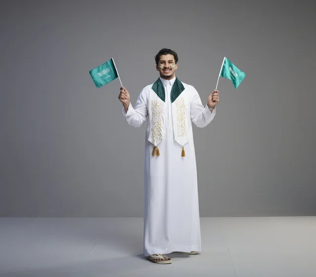 شاب سعودي يحمل الأعلام السعودية في احتفال وطني