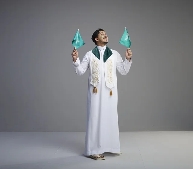شاب سعودي يحتفل بالأعلام السعودية في الاستوديو