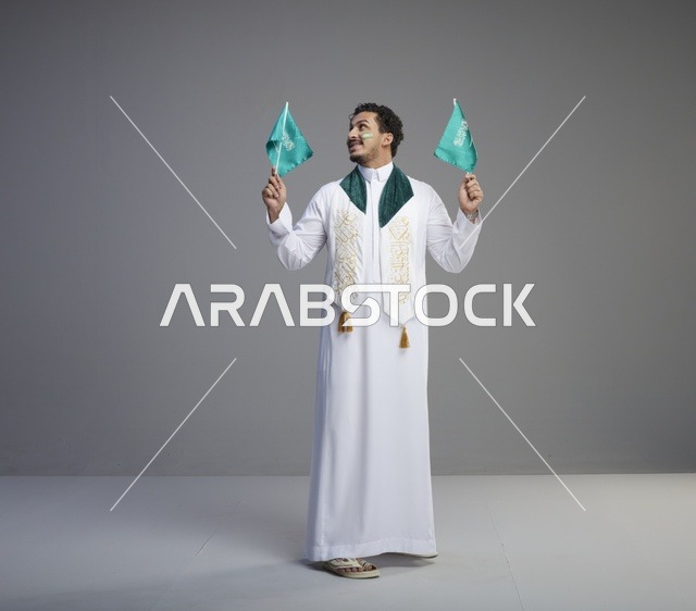 شاب سعودي يحمل الأعلام الوطنية السعودية في يوم التأسيس