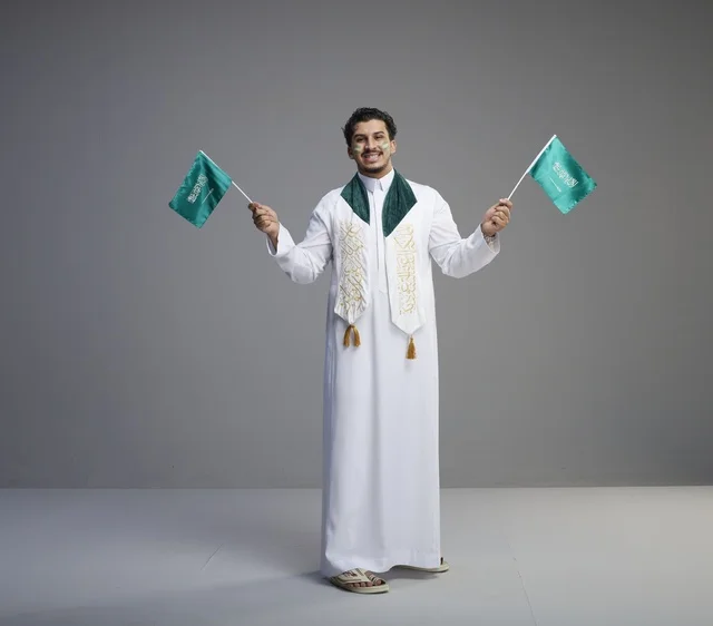 Saudi Man Celebrating National Day with Flags Studio
