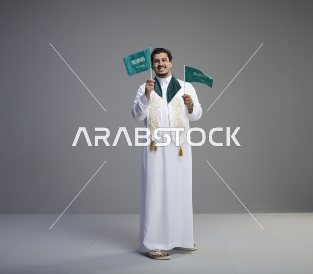 شاب سعودي يحمل الأعلام الوطنية في الاستوديو