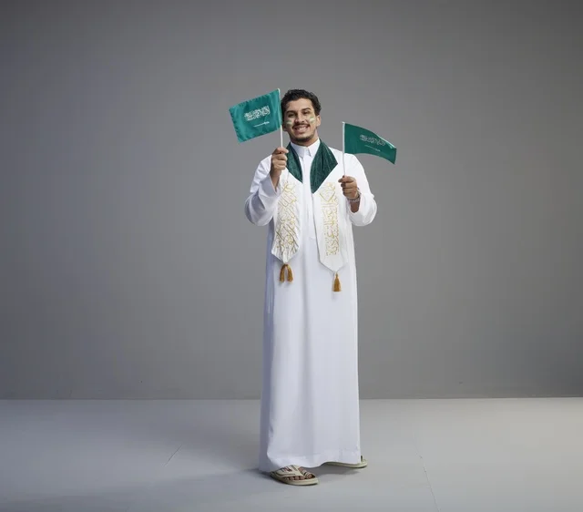 Saudi Man Holding National Flags in Studio Setting