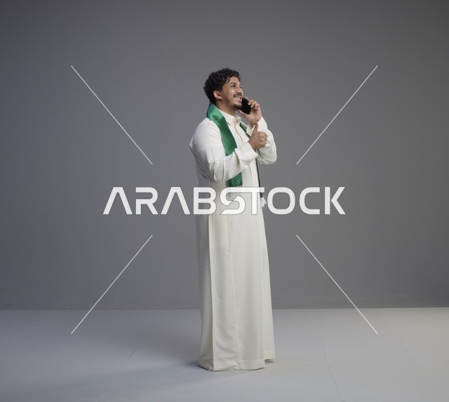 شاب سعودي يتحدث بالهاتف مع وشاح اليوم الوطني