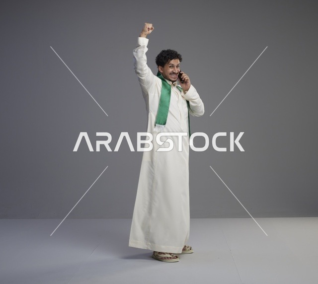 شاب سعودي يحتفل أثناء التحدث بالهاتف الذكي في الاستوديو