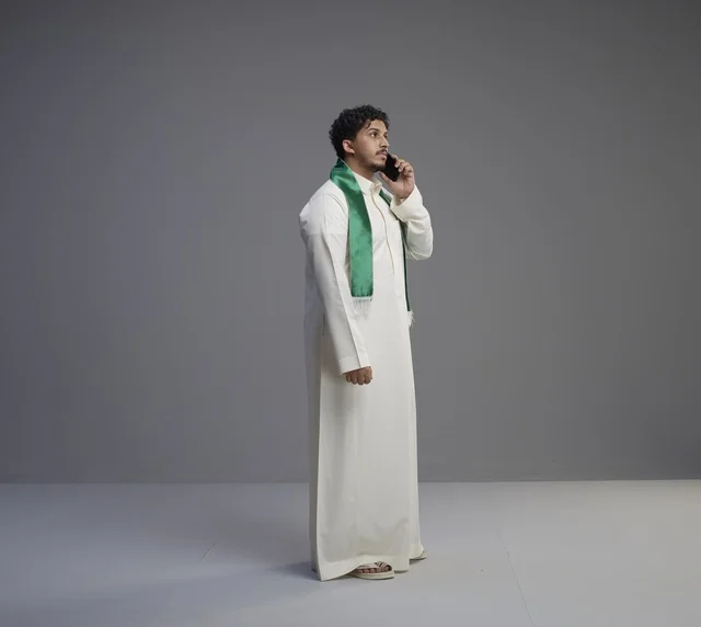شاب سعودي بالثوب يتحدث عبر الهاتف الذكي