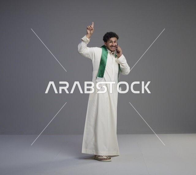 شاب سعودي يتحدث بالهاتف الذكي بالثوب التقليدي