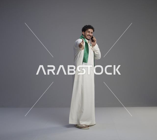 شاب سعودي يتحدث بالهاتف الذكي ويشير بالإبهام