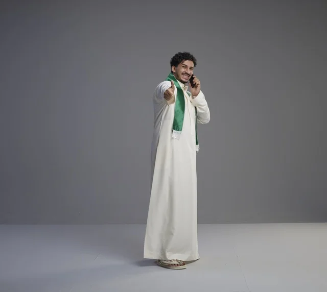 شاب سعودي يتحدث بالهاتف الذكي ويشير بالإبهام