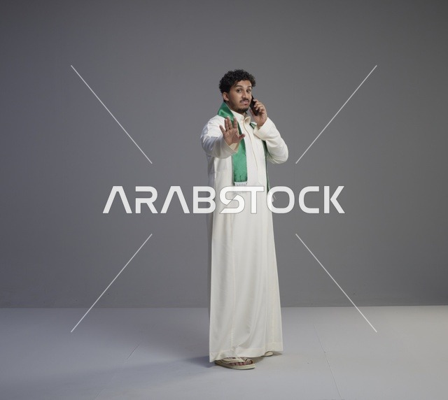 شاب سعودي يتحدث بالهاتف ويشير بالتوقف