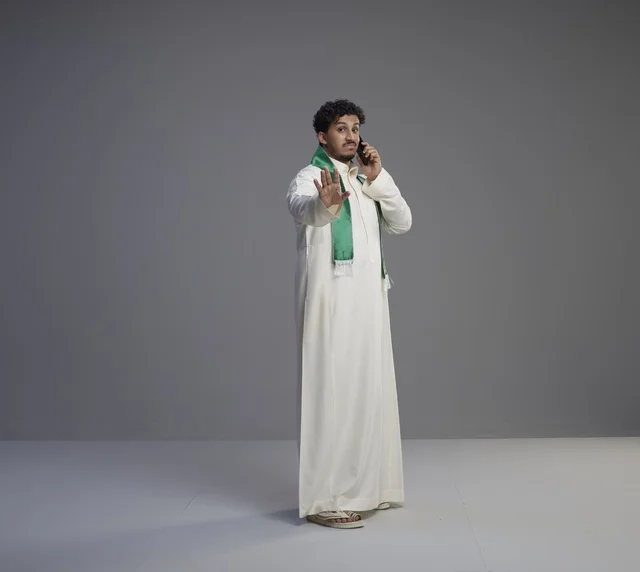 شاب سعودي يتحدث بالهاتف ويشير بالتوقف