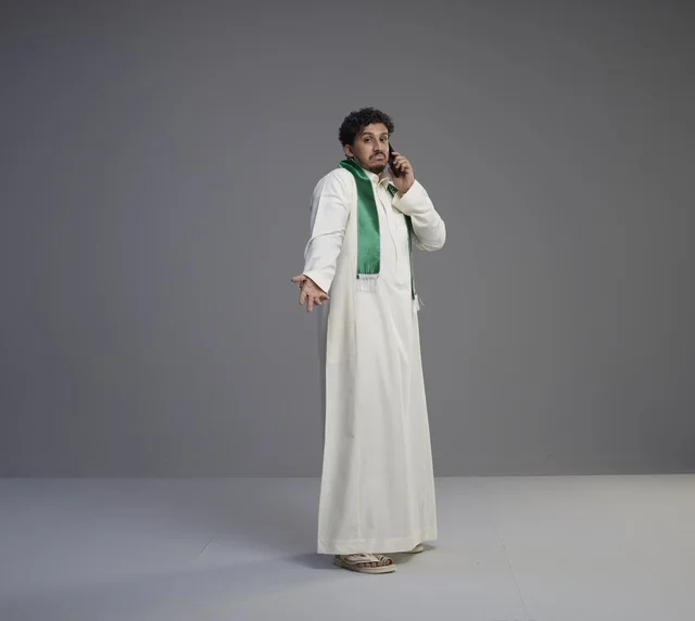 Saudi Man Talking on Smartphone in Studio Grey Background