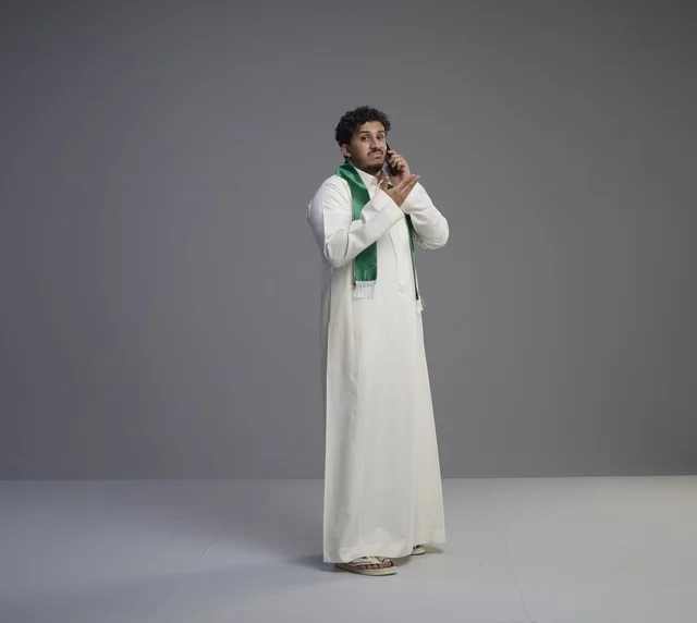 Saudi Man in Traditional Thobe Talking on Smartphone