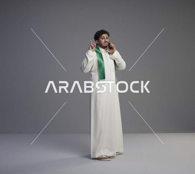شاب سعودي يتحدث بالهاتف الذكي بالثوب التقليدي