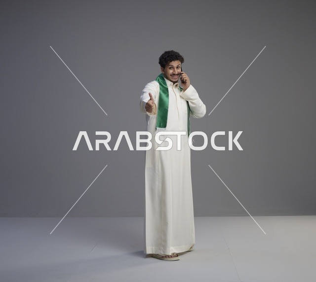 شاب سعودي بالثوب يتحدث بالجوال ويمد يده للمصافحة