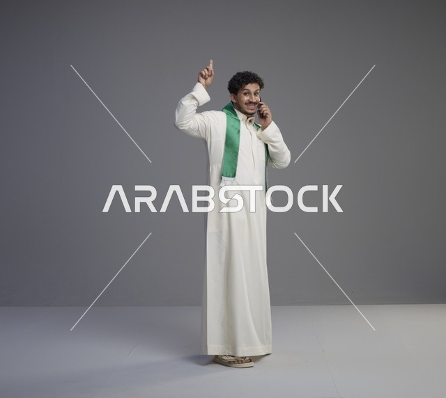شاب سعودي يتحدث بالهاتف الذكي بالثوب التقليدي