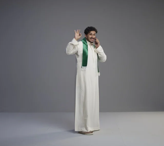 شاب سعودي بالثوب يتحدث بالهاتف الذكي في الاستوديو