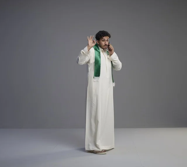 شاب سعودي يتحدث عبر الجوال بوشاح اليوم الوطني