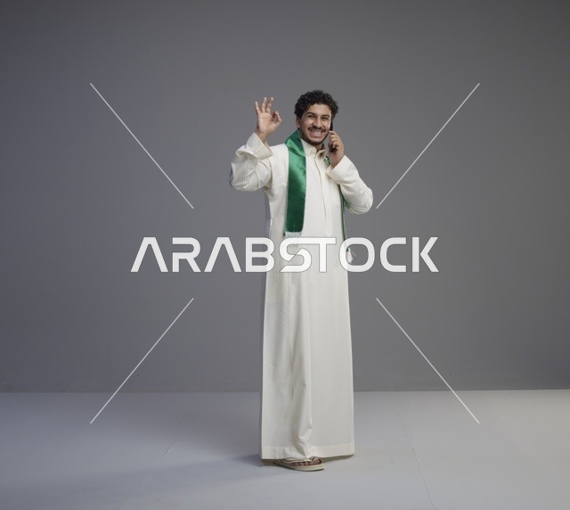 شاب سعودي يتحدث بالهاتف الذكي مع إيماءة موافق